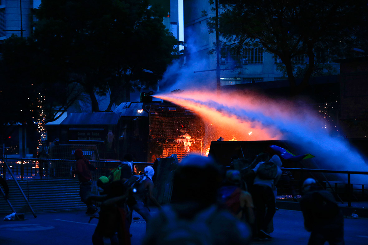 Police operate a water cannon shooting jets of water towards a barricade