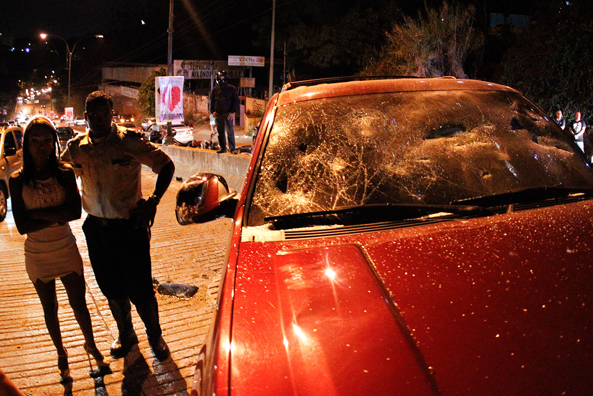 People stand near an SUV that hit anti-government protester Isabel Loaiza