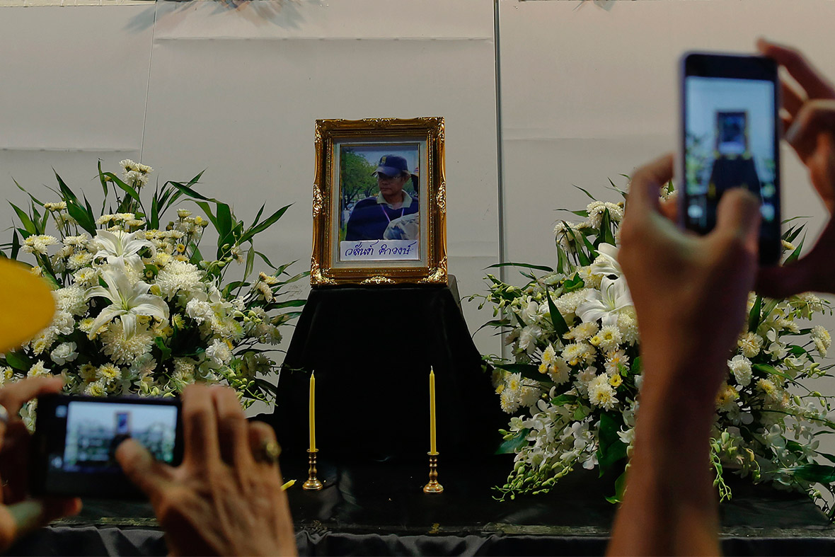 Anti-government protesters take photos of a portrait of their comrade who was killed when gunmen opened fire on a group of protesters driving away from a Bangkok rally