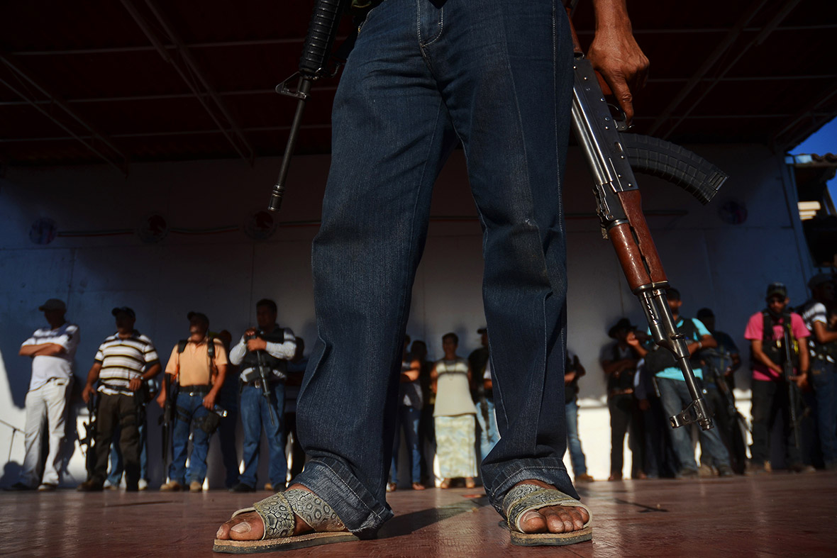 Armed vigilantes stand on a stage in Arteaga, assuring locals they will find Servando Gomez, known as 