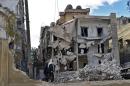 Imagen fechada ayer, 26 de febrero, y facilitada hoy, jueves 27 de febrero, que muestra a unos civiles pasando por un edificio destruído por un ataque aéreo por parte del régimen sirio en el barrio de Kalase en Alepo, Siria. EFE