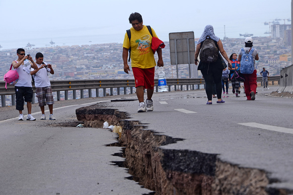 People walk along a large crack in a road in Iquique Chile, a day after the powerful 8.2-magnitude earthquake hit