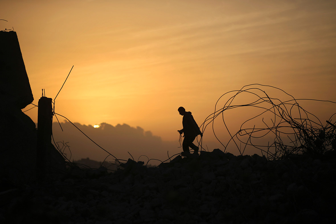A Palestinian man walks over building rubble during sunset in the northern Gaza Strip