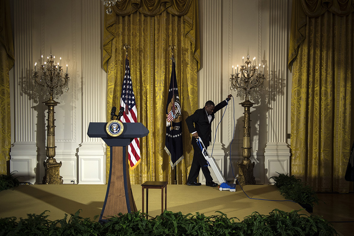 A staff member vacuums a podium before an event in the East Room of the White House in Washington, DC