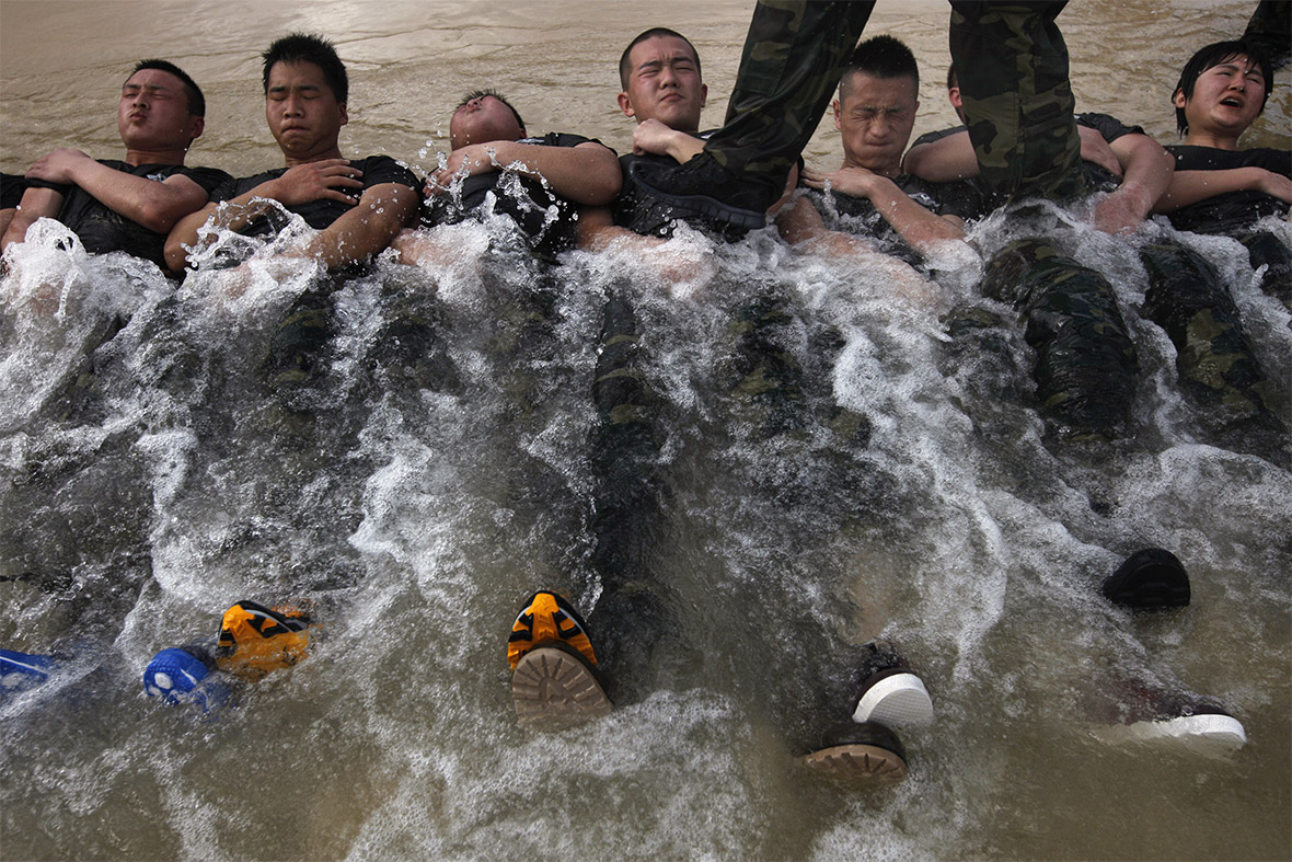 A bodyguard hopeful steps on the stomachs of other trainees during a training session on a beach in Sanya, Hainan province