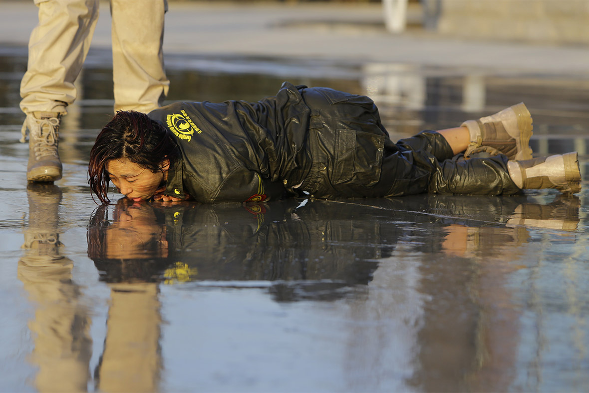 A trainee lies on the ground after she was blasted with water