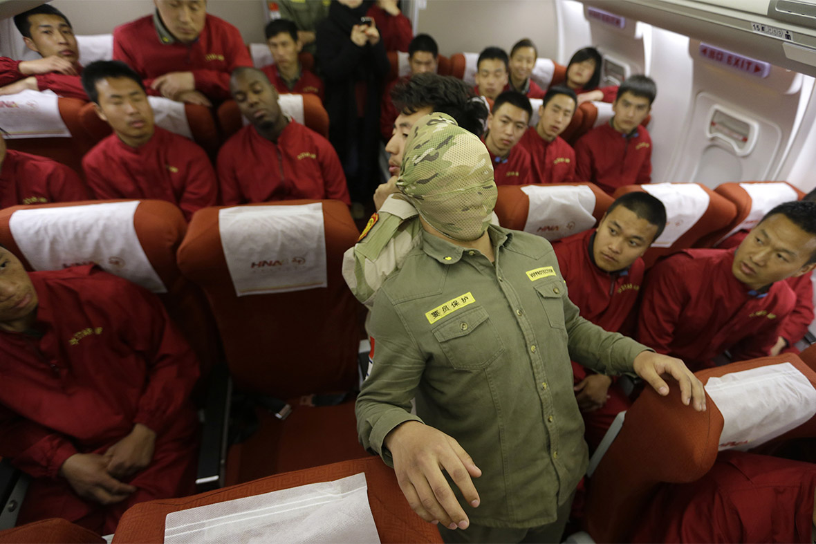 Tianjiao bodyguard school trainees watch their instructor use a scarf to disable a 'hijacker' during a a special flight safety training course inside a scale model of a passenger jet