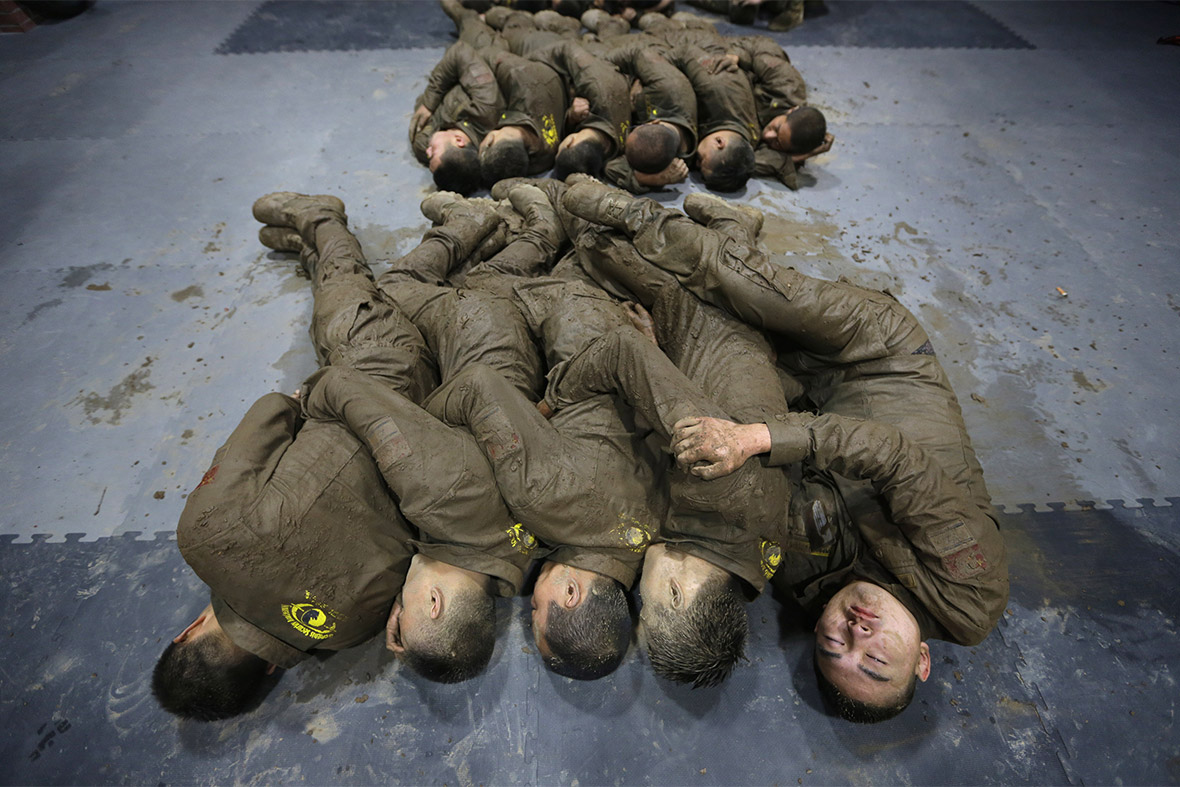 Mud-soaked students huddle together for warmth as they sleep during a break in training