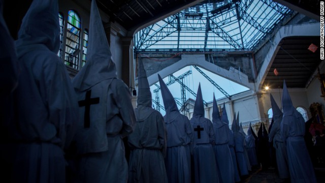 Penitents watch on from a damaged part of the Palo Cathedral during the Maundy Thursday Mass at Palo Cathedral in Palo, Leyte, Philippines, on April 17.