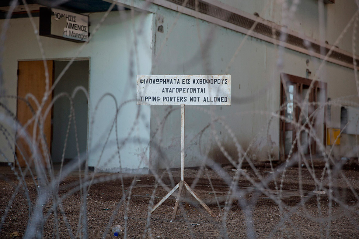 A sign warning passengers not to tip porters is seen through barbed wires at the abandoned Nicosia International Airport