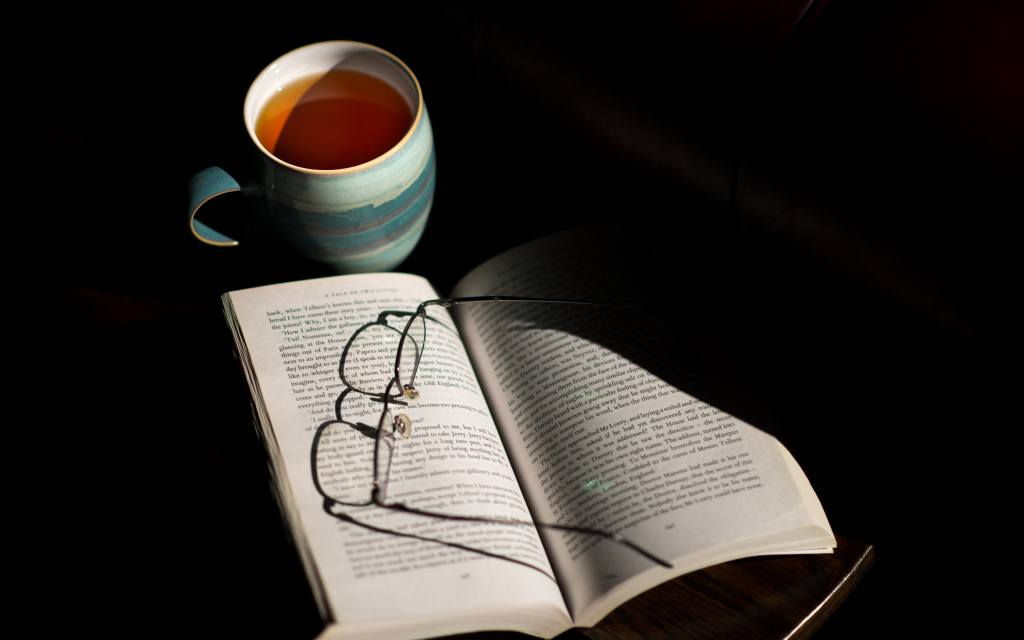 Reading Glasses On Book With Hot Tea Drink