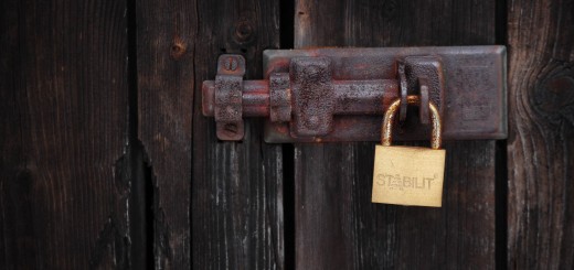 A padlock closes a wooden door at a grav