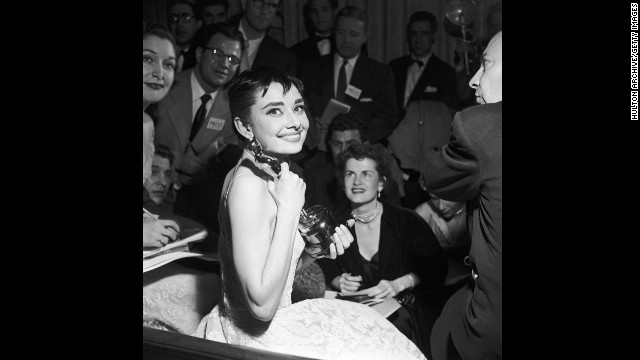 Audrey Hepburn is surrounded by reporters as she holds her best actress Oscar for "Roman Holiday."