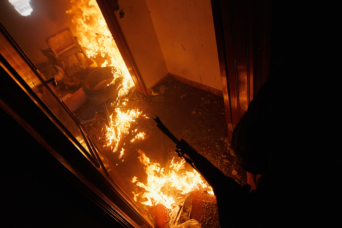 April 20, 2011: A rebel fighter covers a burning room containing ensconced government loyalist troops who were firing on them during house-to-house fighting on Tripoli Street in Misrata