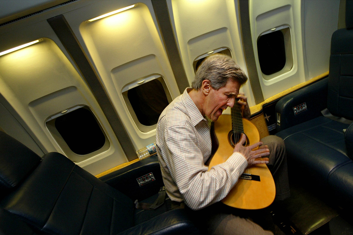 February 18, 2004: Democratic presidential candidate Senator John Kerry plays his guitar in flight enroute to Washington, DC