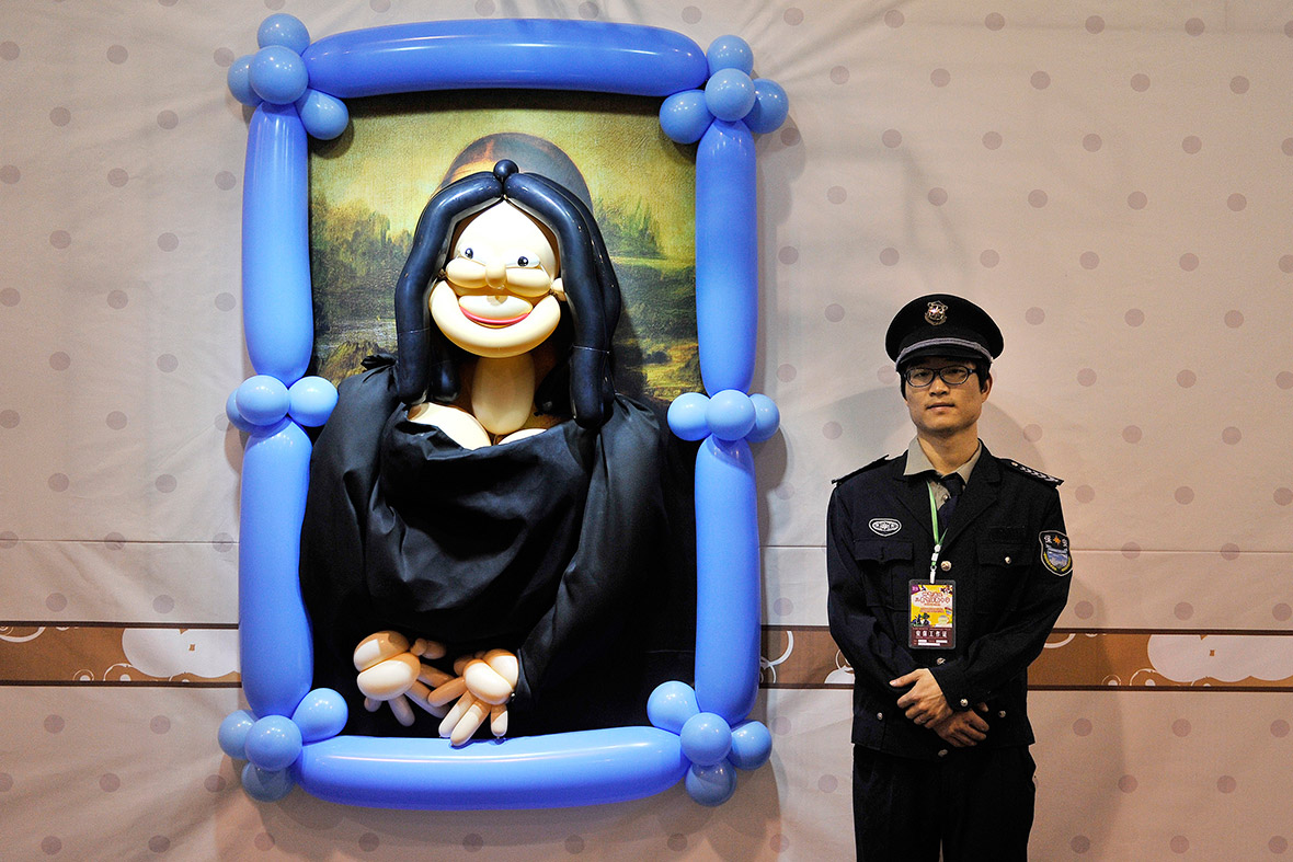 A security guard stands next to a version of the Mona Lisa at a balloon-themed carnival in Hefei, Anhui province, China.