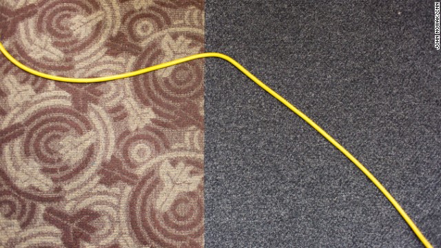 A floor cleaner's power cable crosses the carpet.