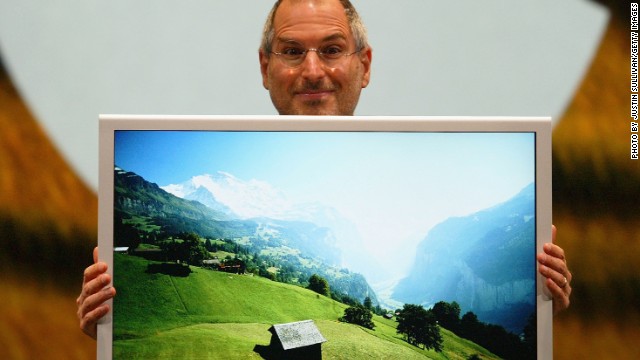 Jobs posed here with a new flat-panel display, the first 30-inch model designed for the personal computer. He also announced the 2005 release of OSX Tiger.
