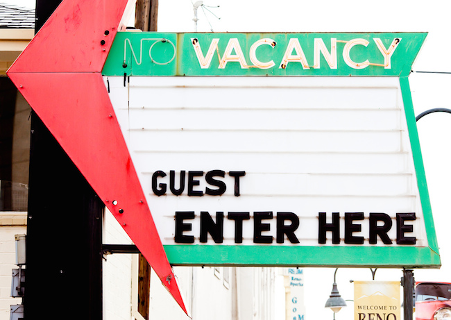 Image of motel sign reading Guest Enter Here