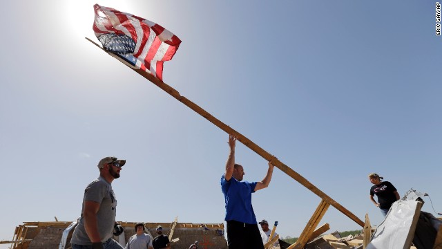 Justin Shaw, left, helps Nick Conway erect a flagpole April 28 at his destroyed home in Vilonia.