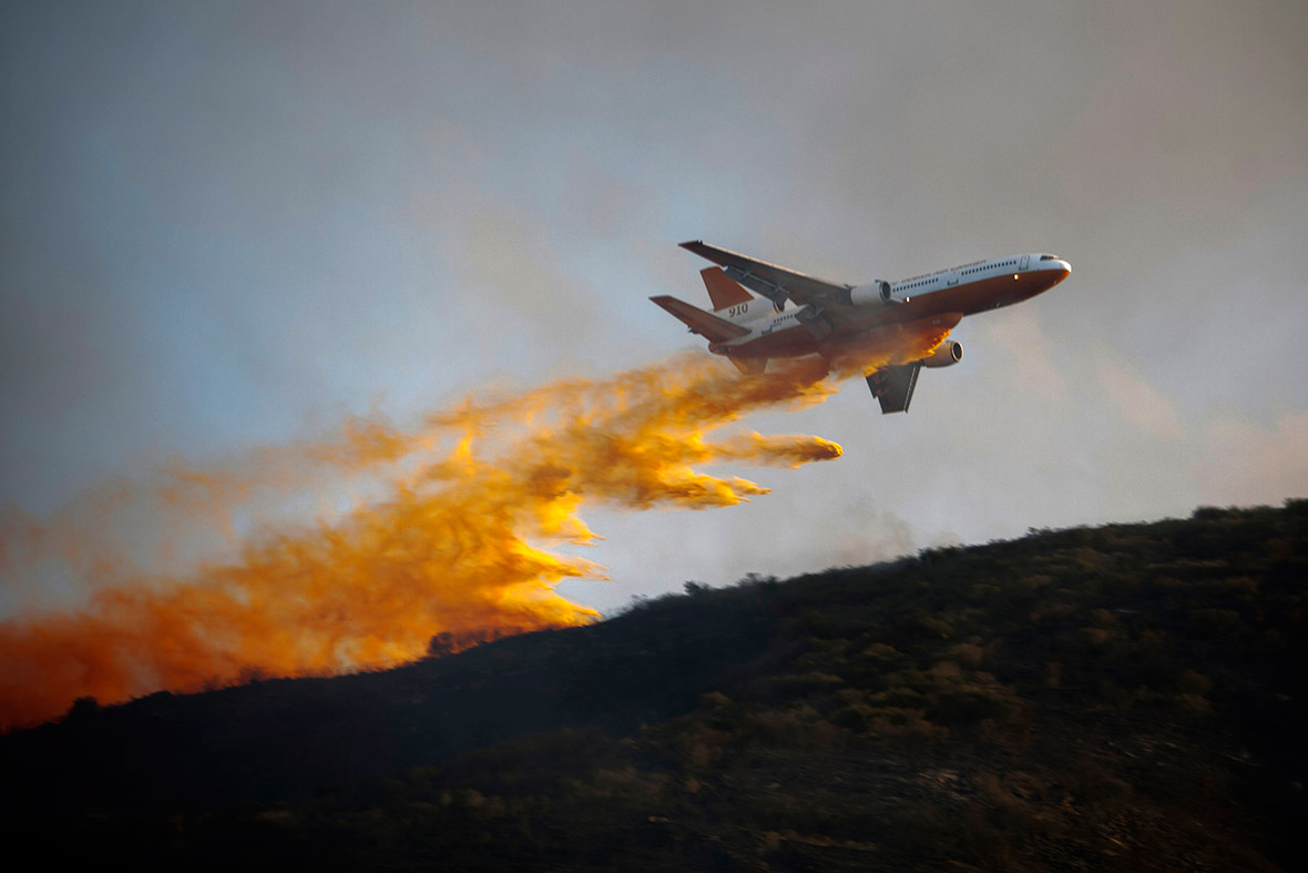A DC-10 Super Tanker aircraft dumps flame retardant on a blaze in San Marcos, California.