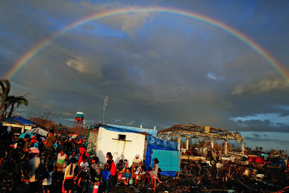 November 15, 2013: A rainbow appears above Typhoon Haiyan survivors desperate to catch a flight from Tacloban airport
