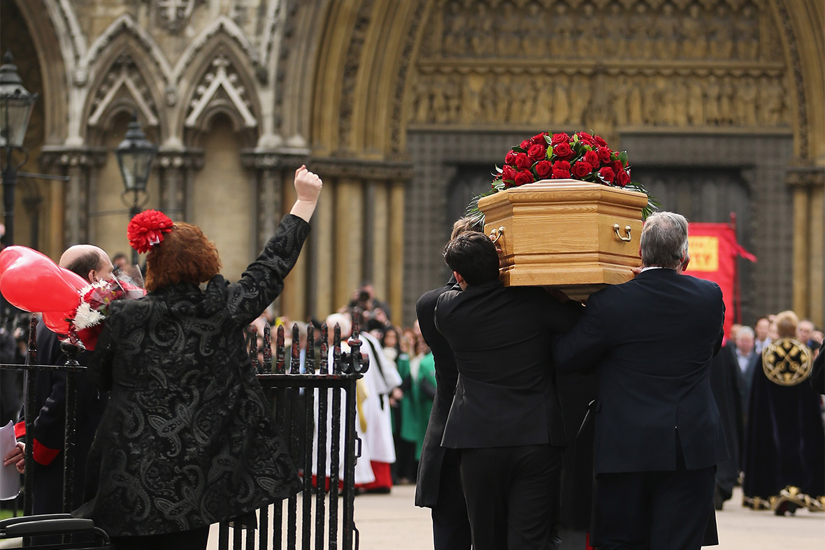 A woman raises her fist in salute as Tony Benn's coffin is carried into the grounds of Westminster Abbey