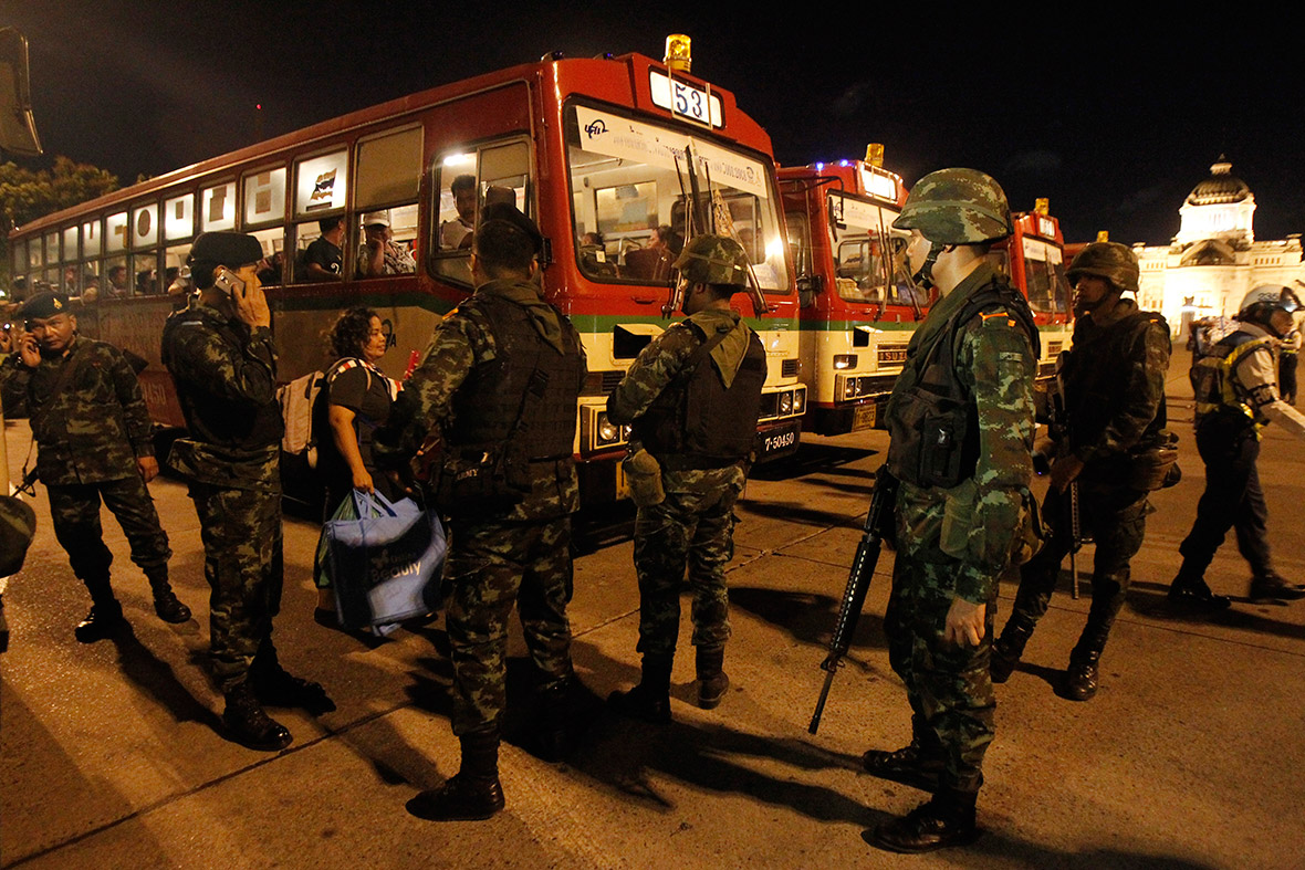 Thai soldiers watch as anti-government protesters board a bus to head home, from the Royal Plaza in Bangkok
