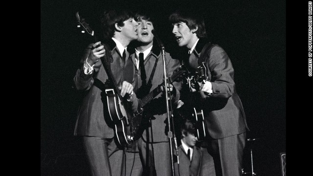 From left, McCartney, Lennon and Harrison share a microphone as they sing a song at Carnegie Hall.