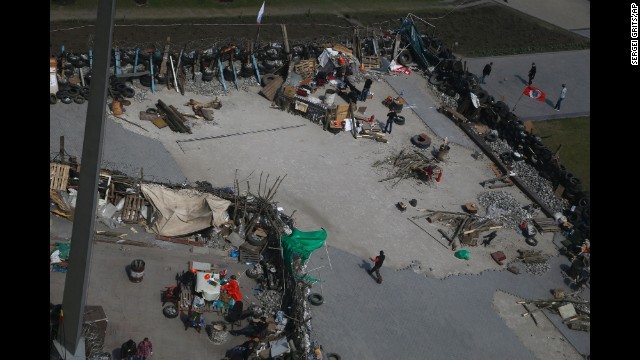 People walk around barricades April 18 set up at the regional administration building that was seized earlier in Donetsk.