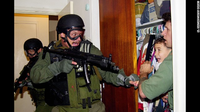 During a raid at a Miami home in 2000, armed federal agents confront Elian Gonzalez, 6, and one of the men who helped rescue the boy. Gonzalez watched his mother drown when the boat smuggling them from Cuba capsized. Under international law, U.S. authorities were required to return the boy to his father in Cuba. 