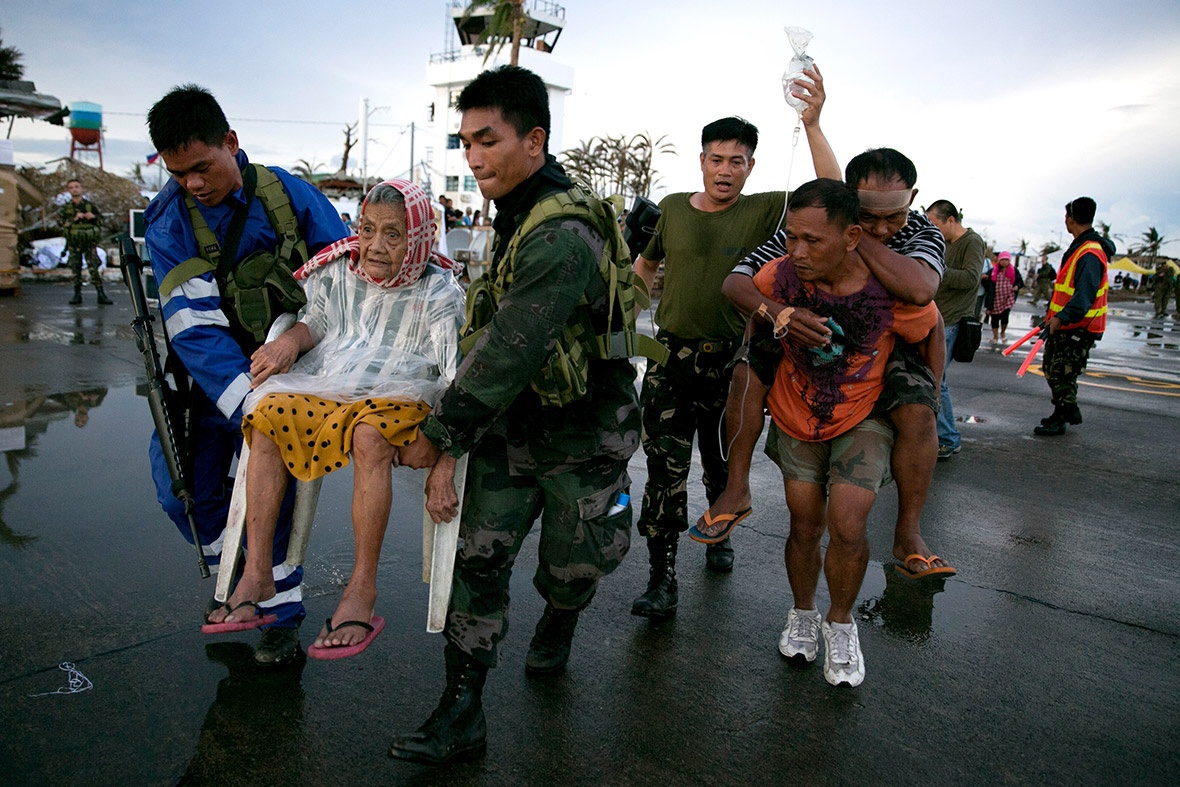 November 12, 2013: An elderly woman and an injured man are carried to a waiting C130 aircraft during the evacuation of hundreds of survivors of typhoon Haiyan from Tacloban