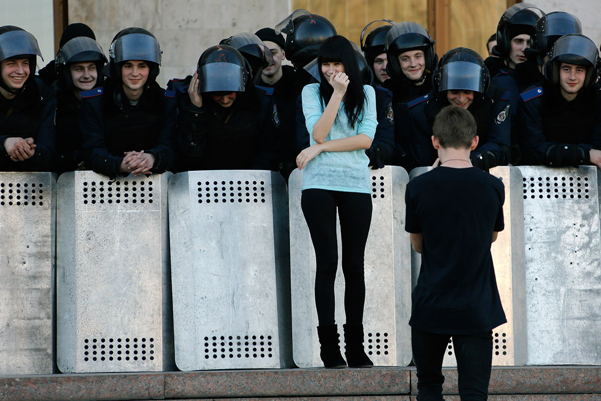 A young man takes photos of his girlfriend posing with Ukrainian riot police guarding the regional administration building following a pro-Russian rally in Donetsk