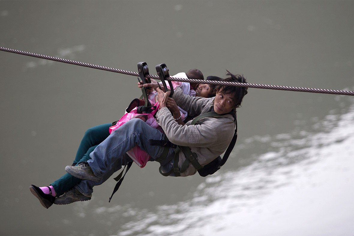 A man, his wife and their child use a zip-line to cross the Nujiang River in Lazimi village of Nujiang Lisu Autonomous Prefecture, China. Residents have been using the zip-line for years to cross the river as there is no bridge nearby