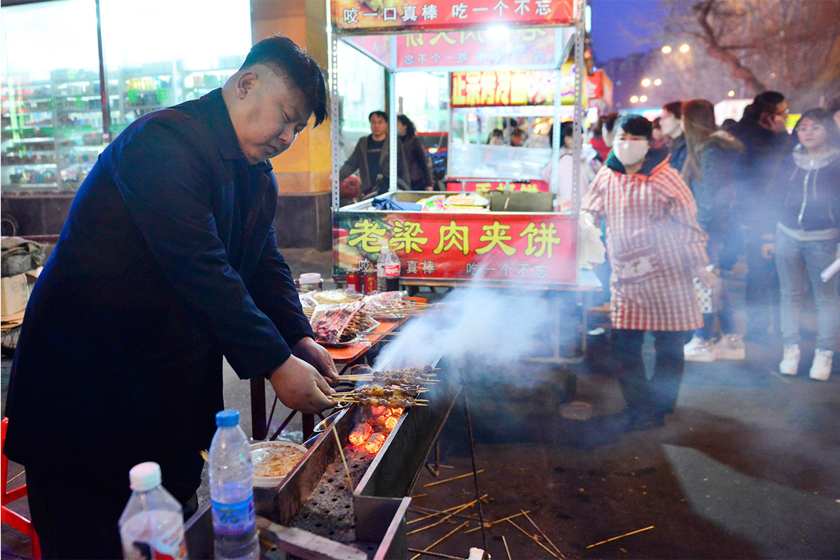 Xia, a 38-year-old lookalike of North Korean leader Kim Jong Un, cooks barbequed lamb at his food stall in Shenyang, Liaoning province, China