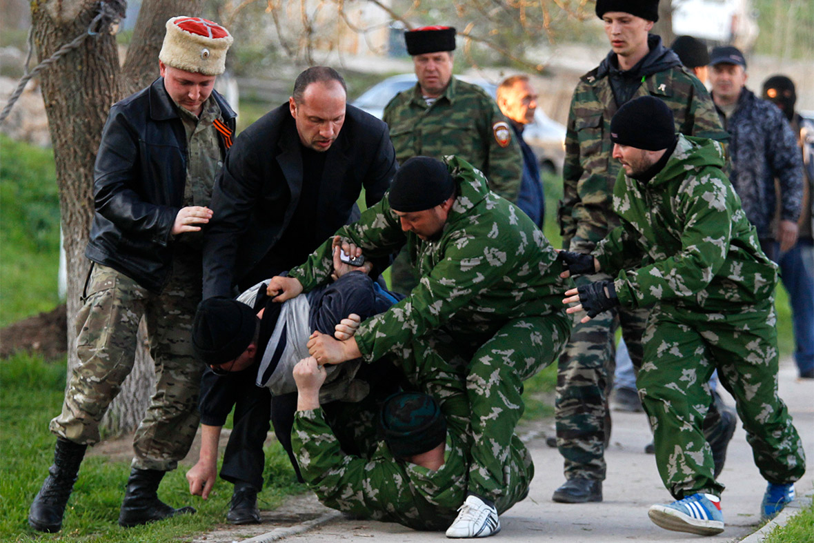 Members of pro-Russian self-defence units detain a man outside a military airbase in the Crimean town of Belbek