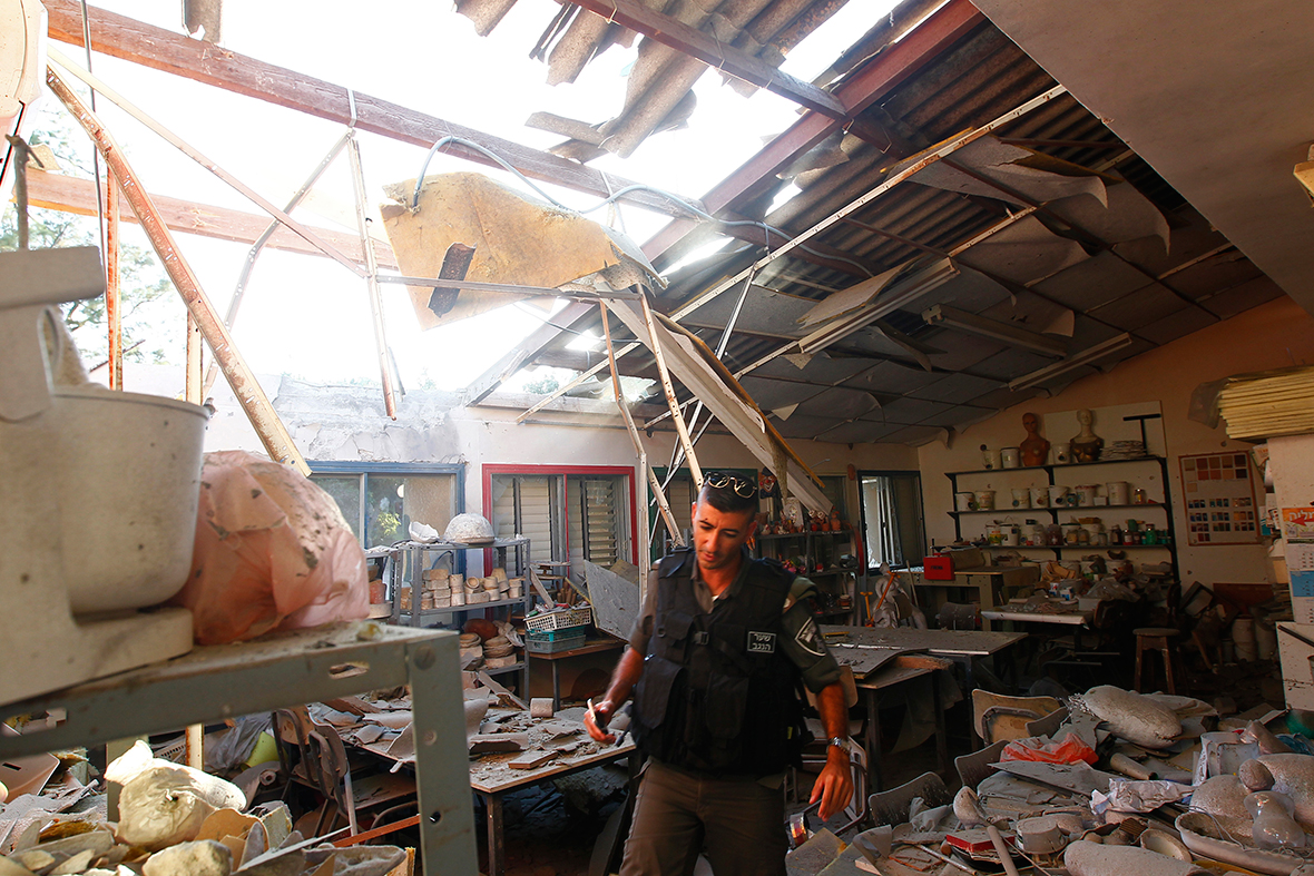 An Israeli border policeman surveys damage caused to a building in a Kibbutz near the border with the Gaza Strip after it was hit by a rocket