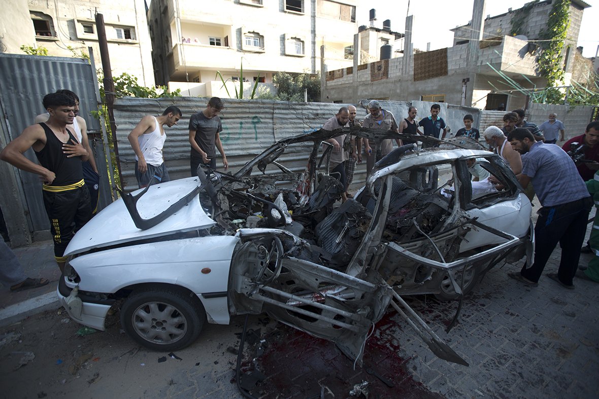 Palestinians inspect the wreckage of a car that had been carrying three Islamic Jihad militants involved in firing rockets