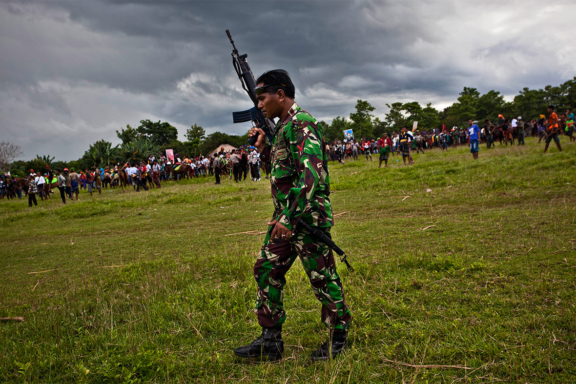 A soldier holds a rifle as a fight breaks out between supporters of the two teams