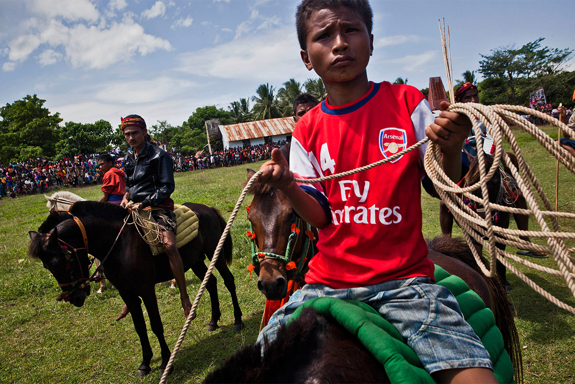 A boy wearing an Arsenal shirt sits on horseback at the festival