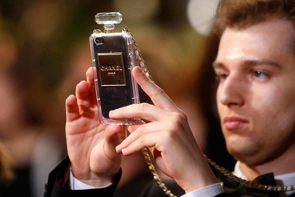 A guest takes a picture with a mobile phone in a Chanel cover as he arrives for the screening of the film 