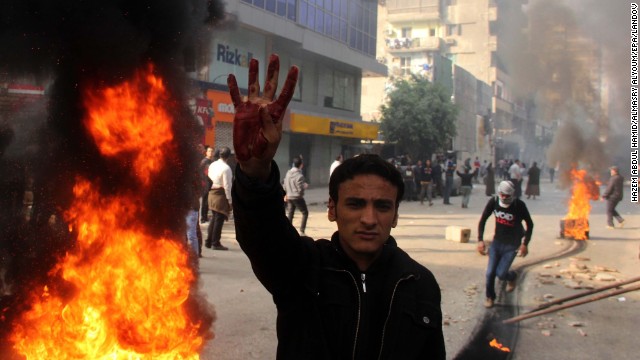 A supporter of the Muslim Brotherhood flashes a four-fingered salute next to burning tires allegedly set ablaze by protesters during clashes with security forces.
