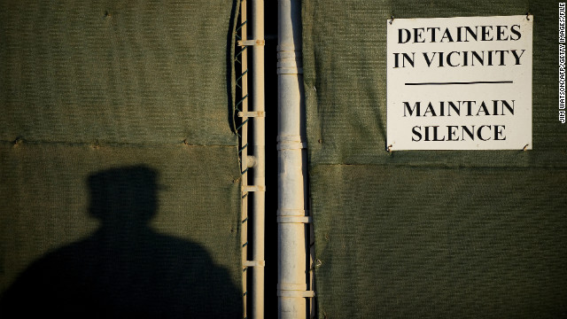 A soldier stands near a placard on the fence line of the detention facility in January 2012. 