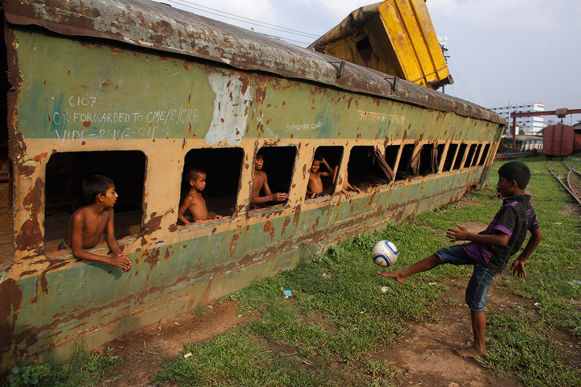 Children play football in front of an abandoned train compartment in Dhaka, Bangladesh