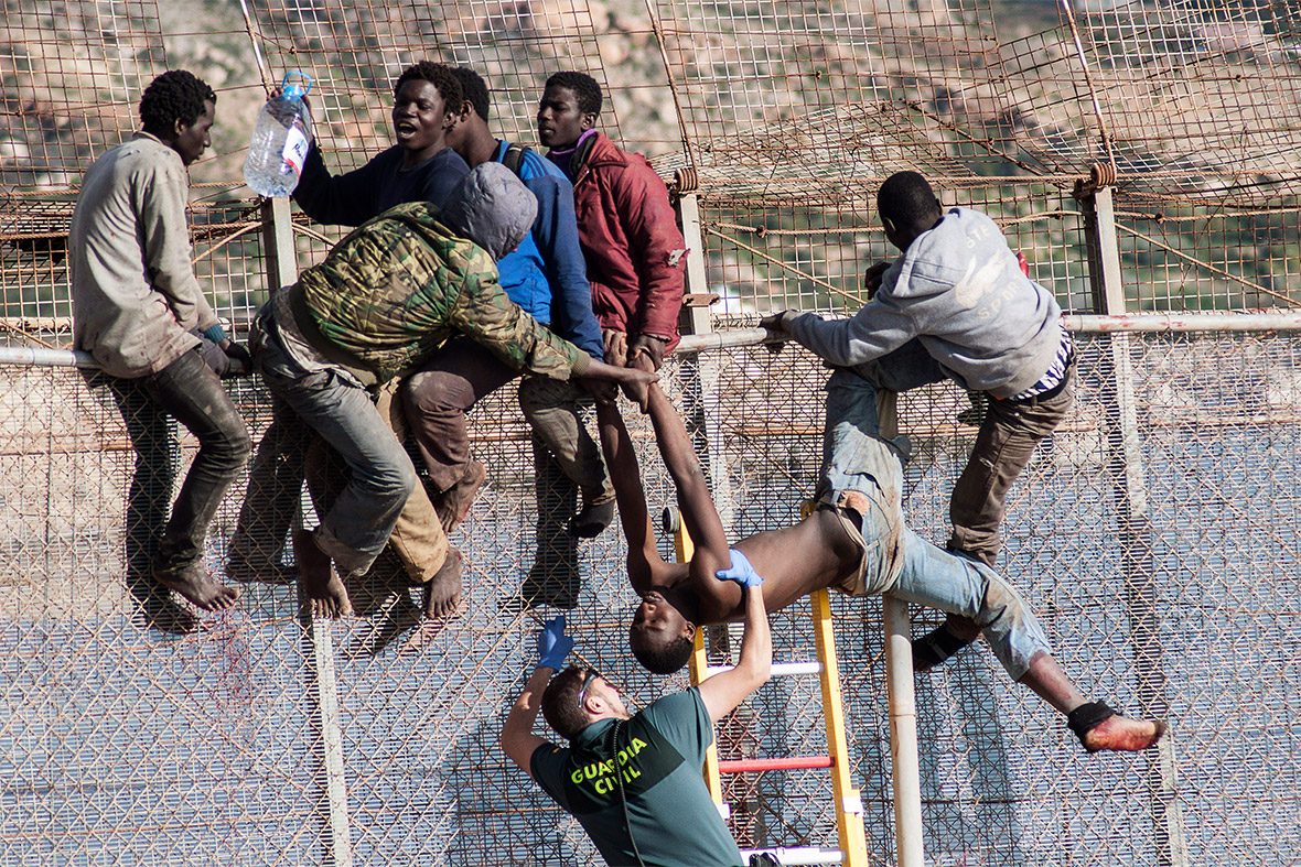 An African migrant is lowered down from the border fence between Morocco and Spain's north African enclave of Melilla during the latest attempt to cross into Spanish territory