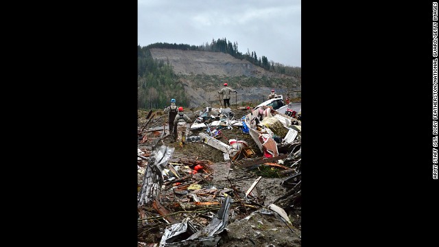 Air National Guard members look out at the hill where the landslide originated while searching the debris field on March 29 in Oso, Washington. 