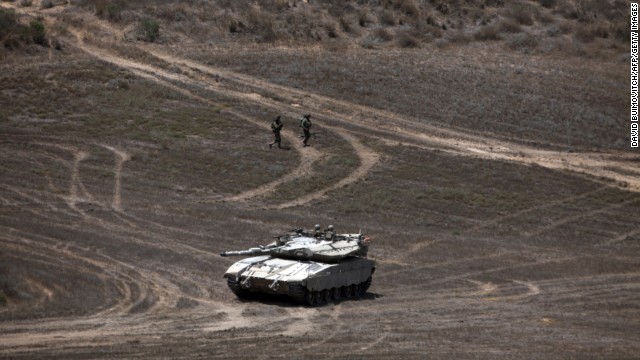 Israeli soldiers walk past a Merkava tank as they patrol a field near Israel's border with Gaza on August 9.