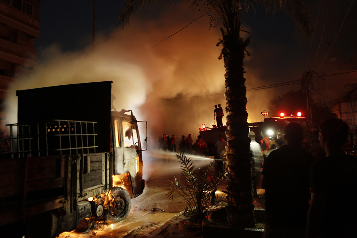 Palestinian firefighters extinguish a blaze at a soap factory after it was hit by an Israeli airstrike