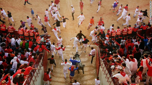 Revelers and bulls run as they enter the bullring on July 13. 