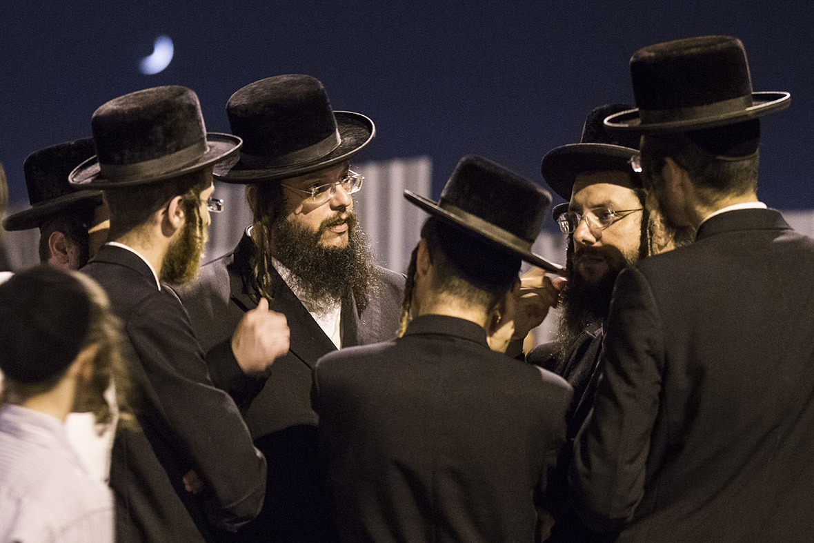 Orthodox Jews talk as they gather outside the house of Eyal Yifrach